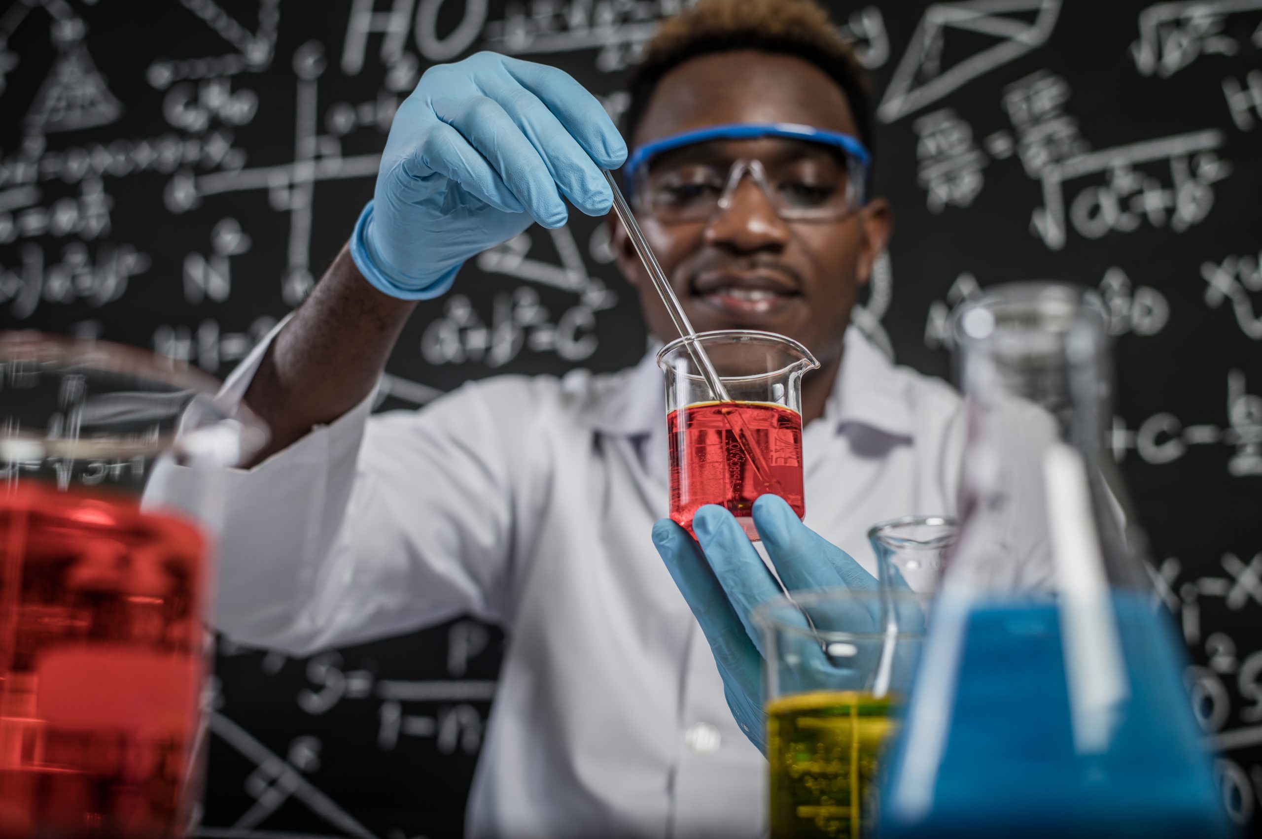 Scientists mixing red chemicals in glass at the laboratory.